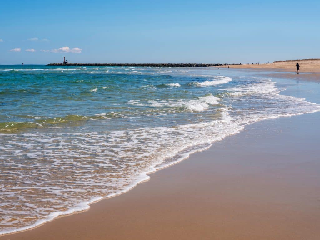 A beach with gentle blue waves sweeping across it.