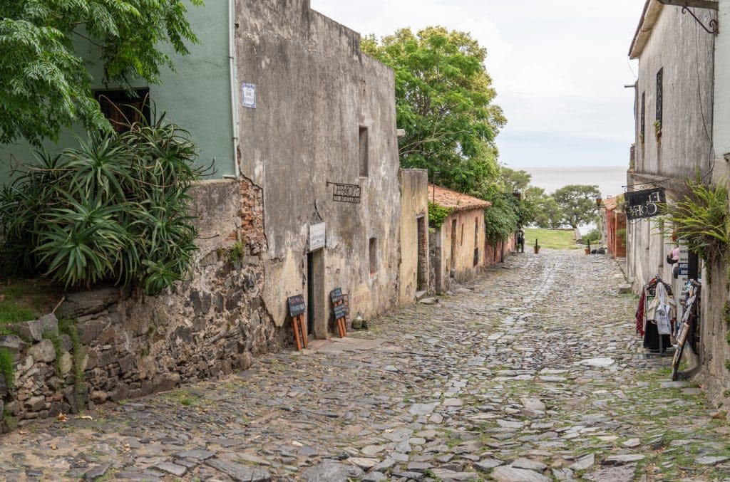 A very old cobbled street in Colonia, surrounded by plain stone buildings.