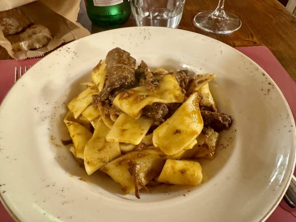 A bowl of thick-cut tagliatelle pasta with chunks of wild boar.