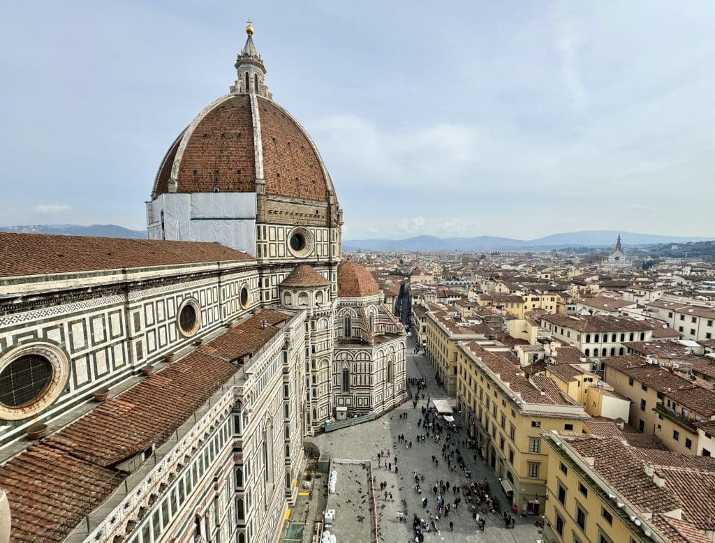 An up-close view of the Duomo of Florence, with its red dome pointing far above all the other buildings.