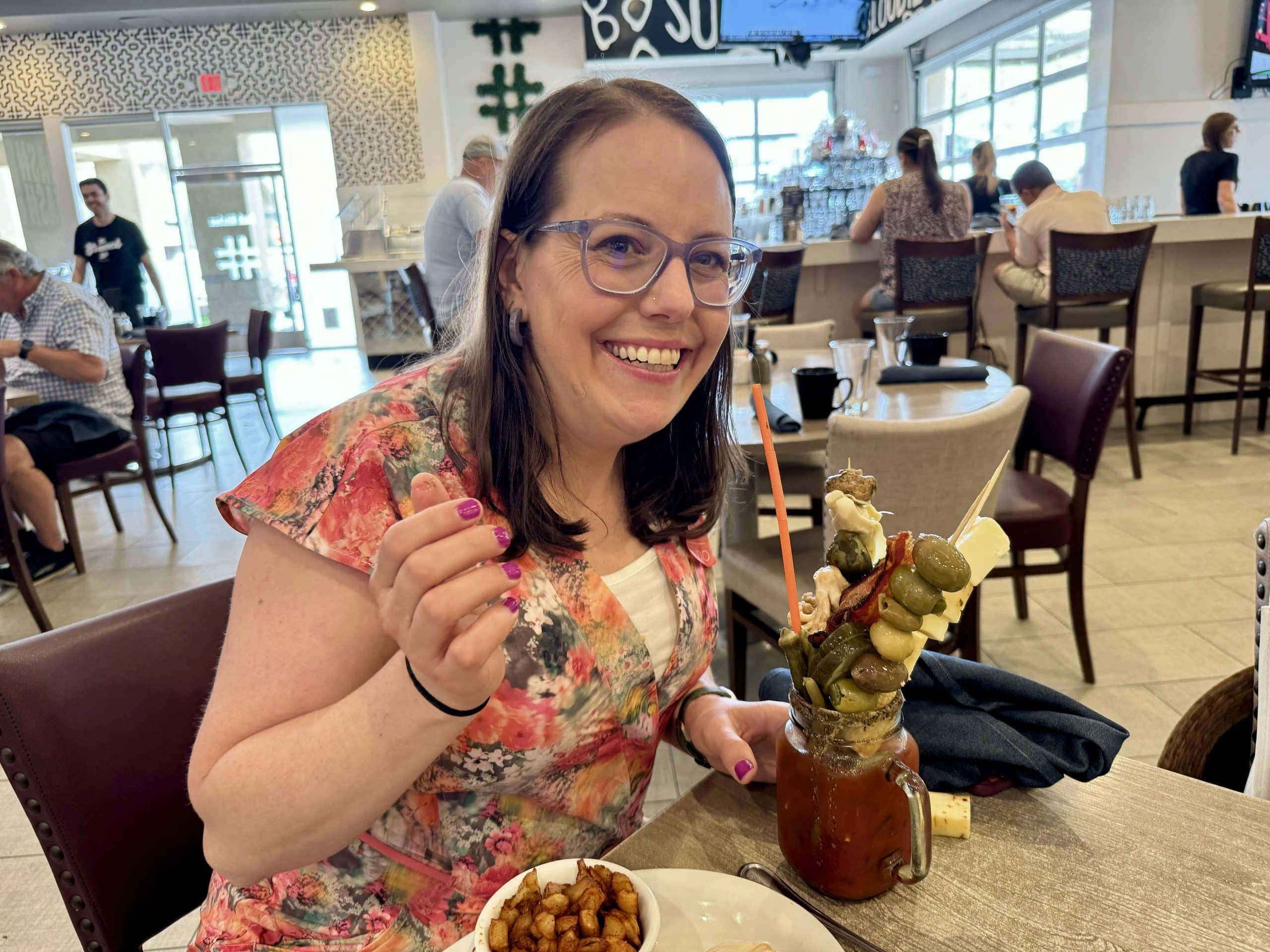 Beth holds up a Bloody Mary piled with tons of cheese, pickled vegetables, olives, fried items, and more.