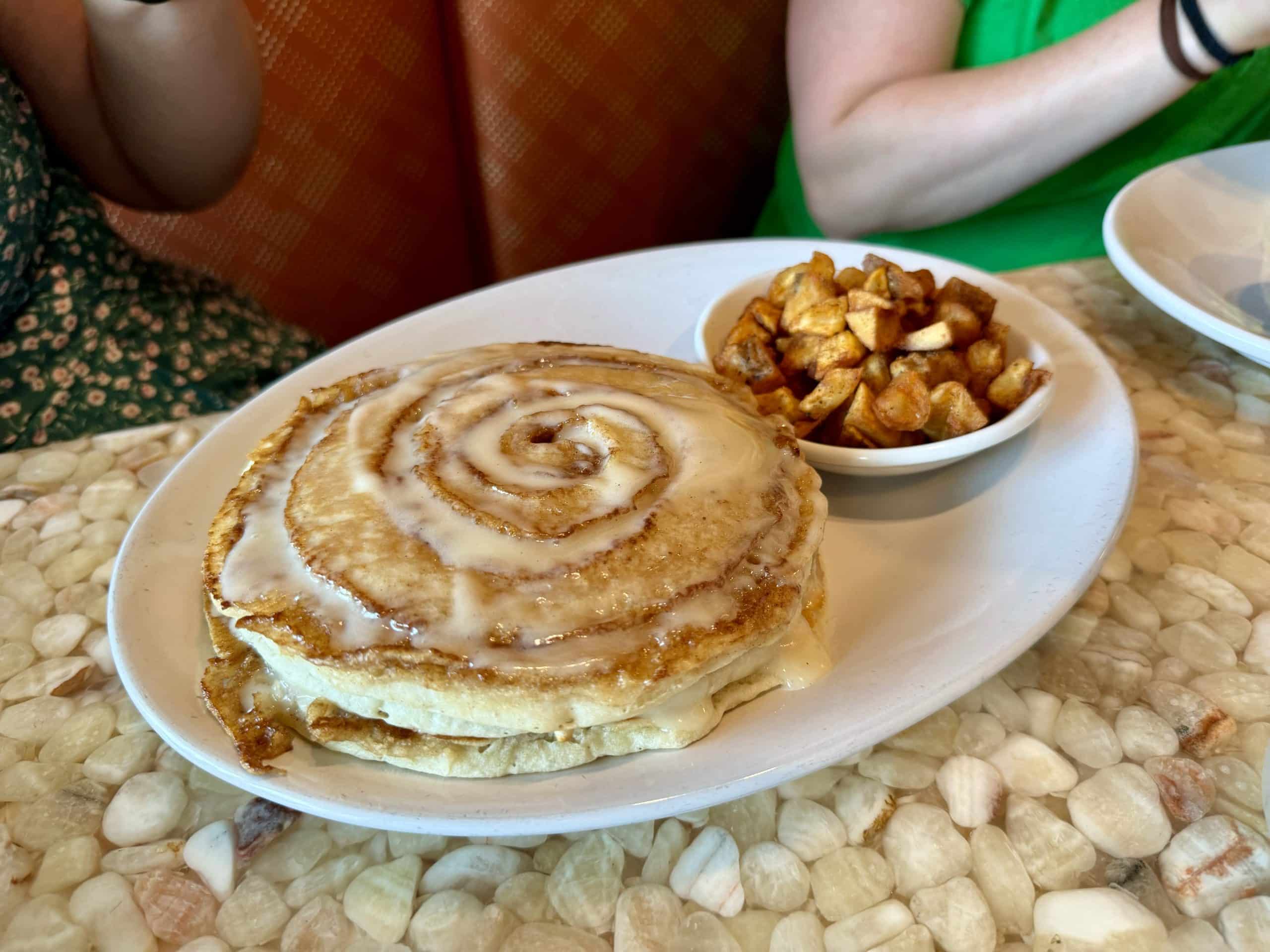 Pancakes that look like a giant spiral cinnamon bun, topped with icing.