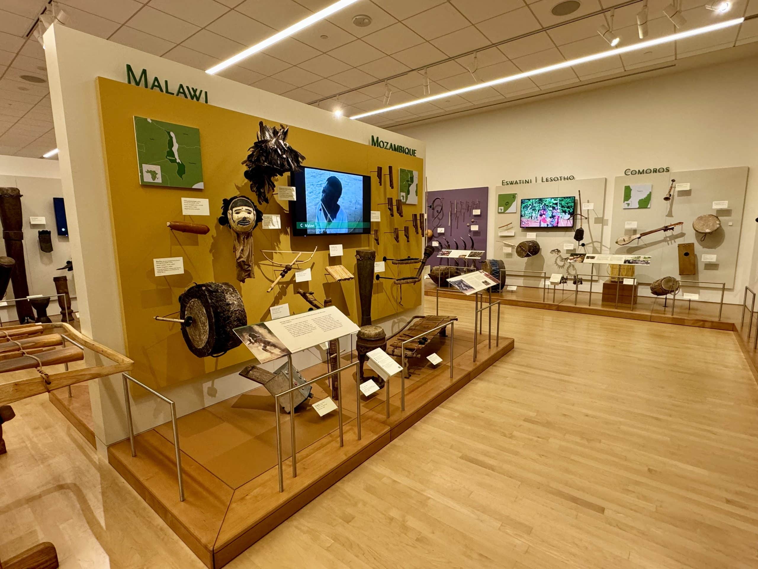 A museum display of musical instruments from Malawi and Mozambique, with Eswatini and Comoros in the background.