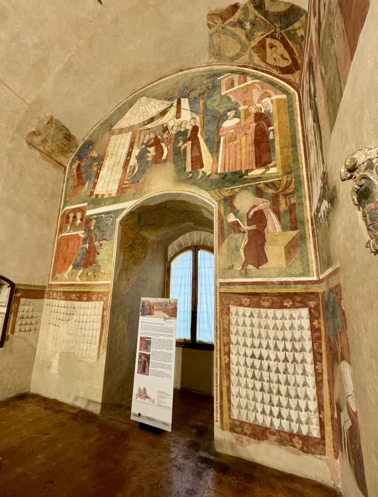 The inside of a museum: a wall painted with frescoes of religious monks and locals.