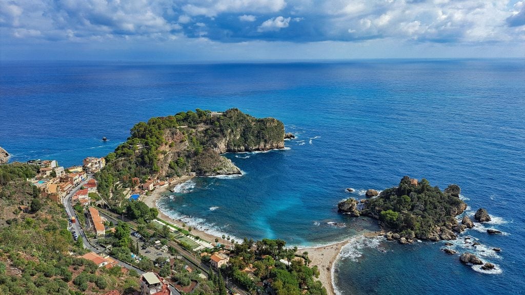 A view of the little island connected by a sandy beach to shore in Taormina.
