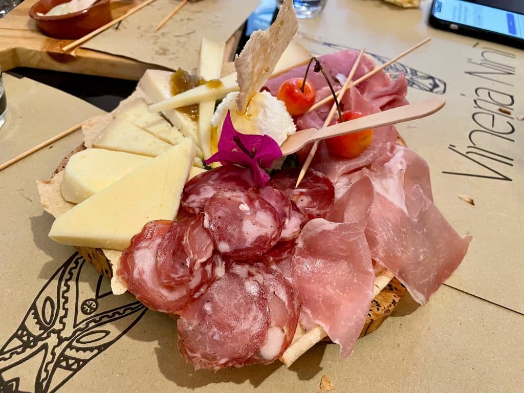 A tagliere (plate of cured meats and cheeses) filled with Sardinian hams, soft cheeses, and hard cheeses.