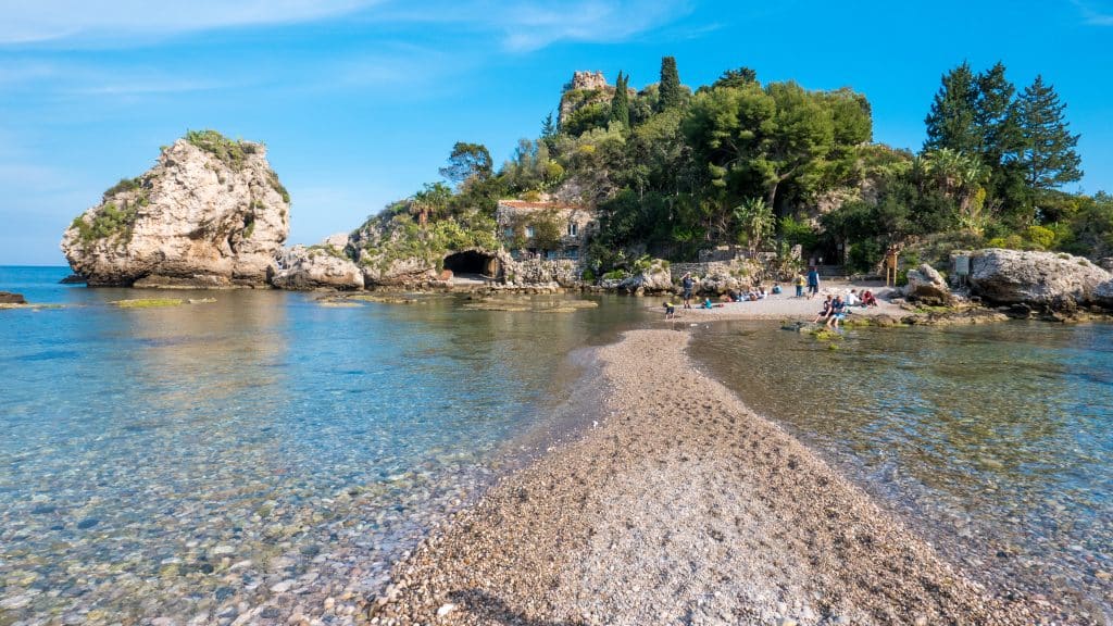A narrow sandy beach path leading to an island.