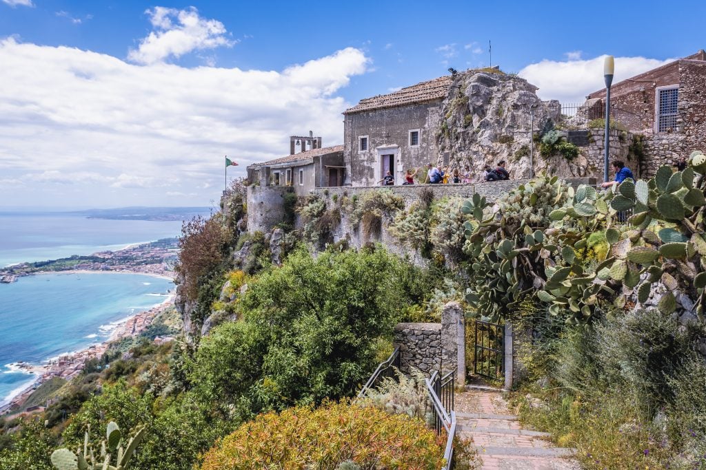 A rocky church on top of a hill overlooking the sea in Taormina.