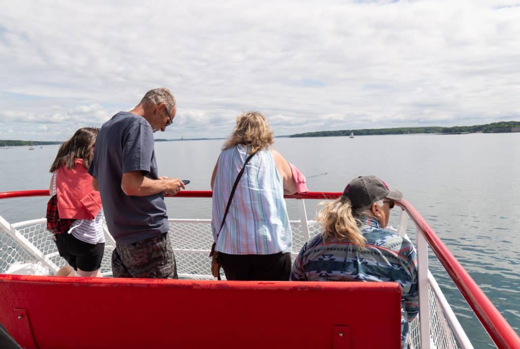 Four people on the bow of a ferry off the coast of Maine, looking at islands.
