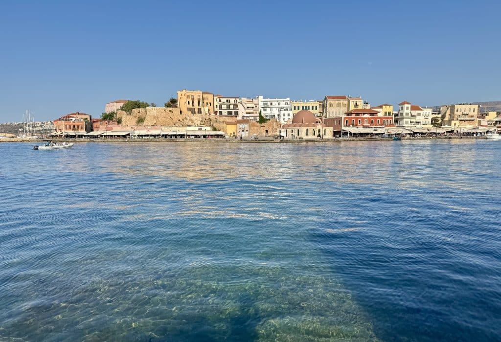 Chania's bright blue harbor, with a small earth-toned city in the background.