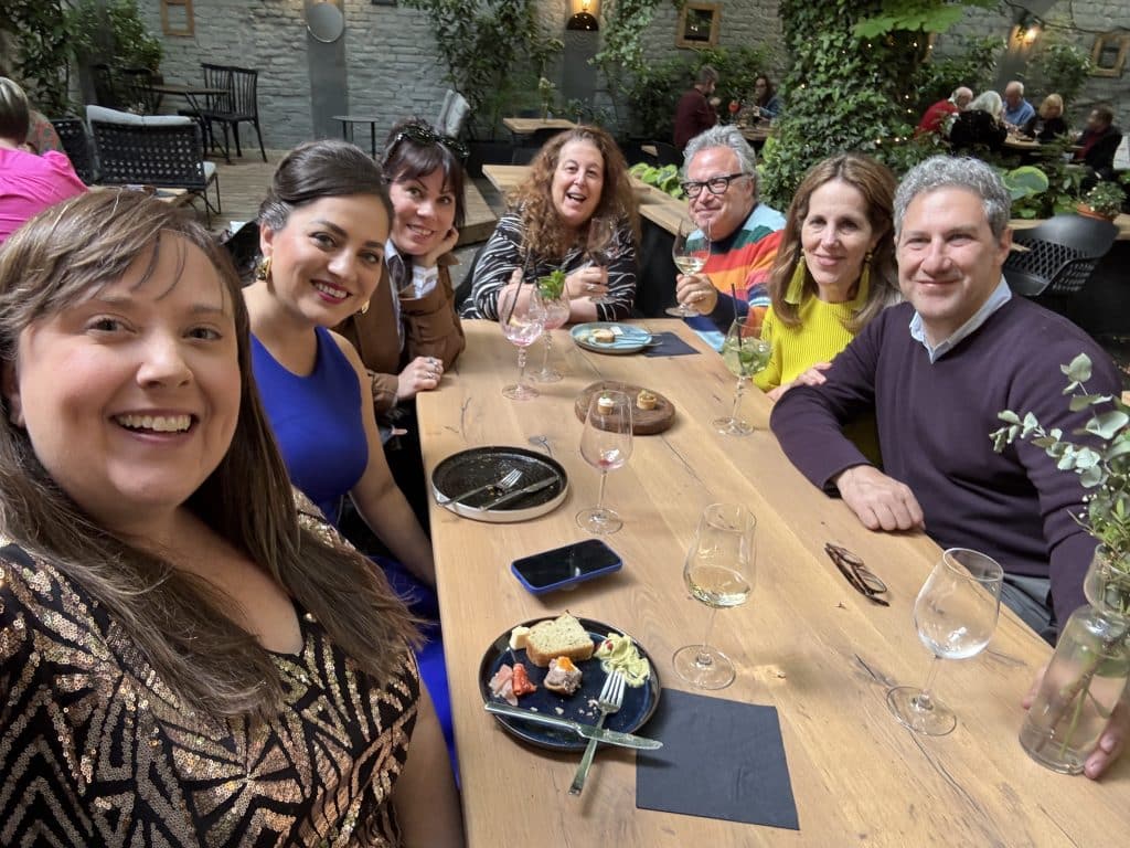 A group of friends sitting and eating at a big table in a courtyard outside.
