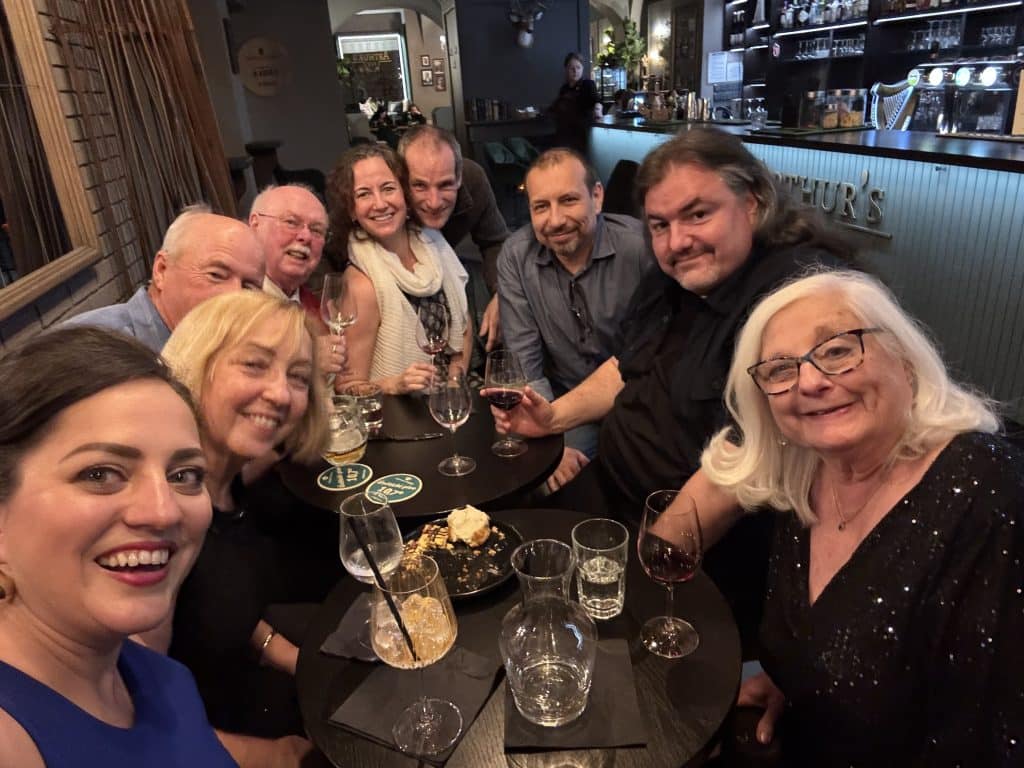 Kate and a group of friends around a table drinking cocktails.