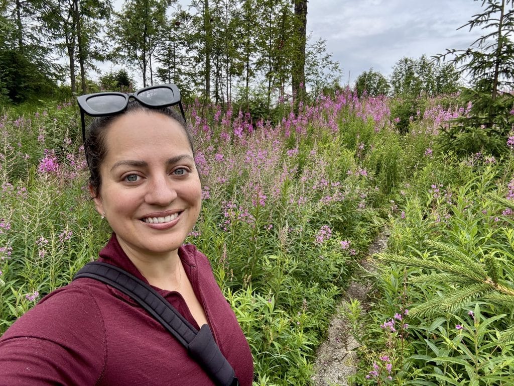 Kate hiking on a trail surrounded by purple wildflowers.