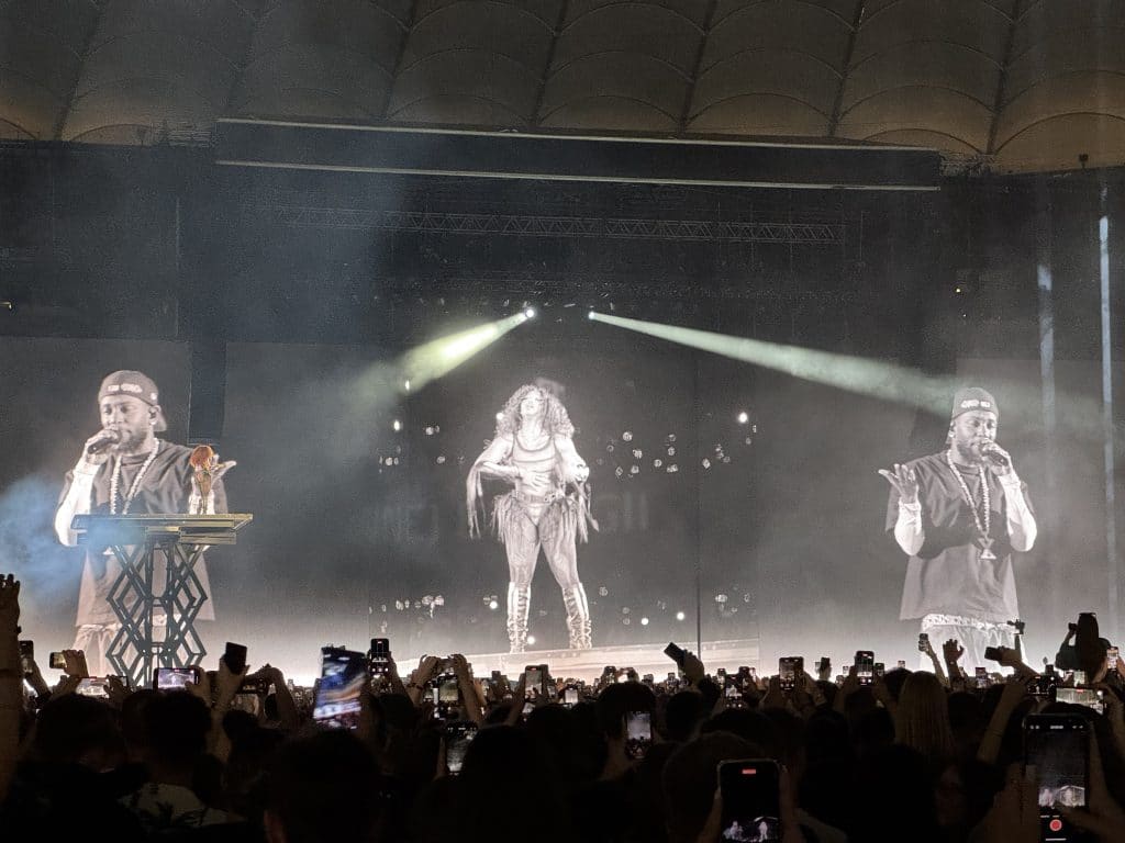 Kendrick Lamar and SZA performing on high platforms on a stage.
