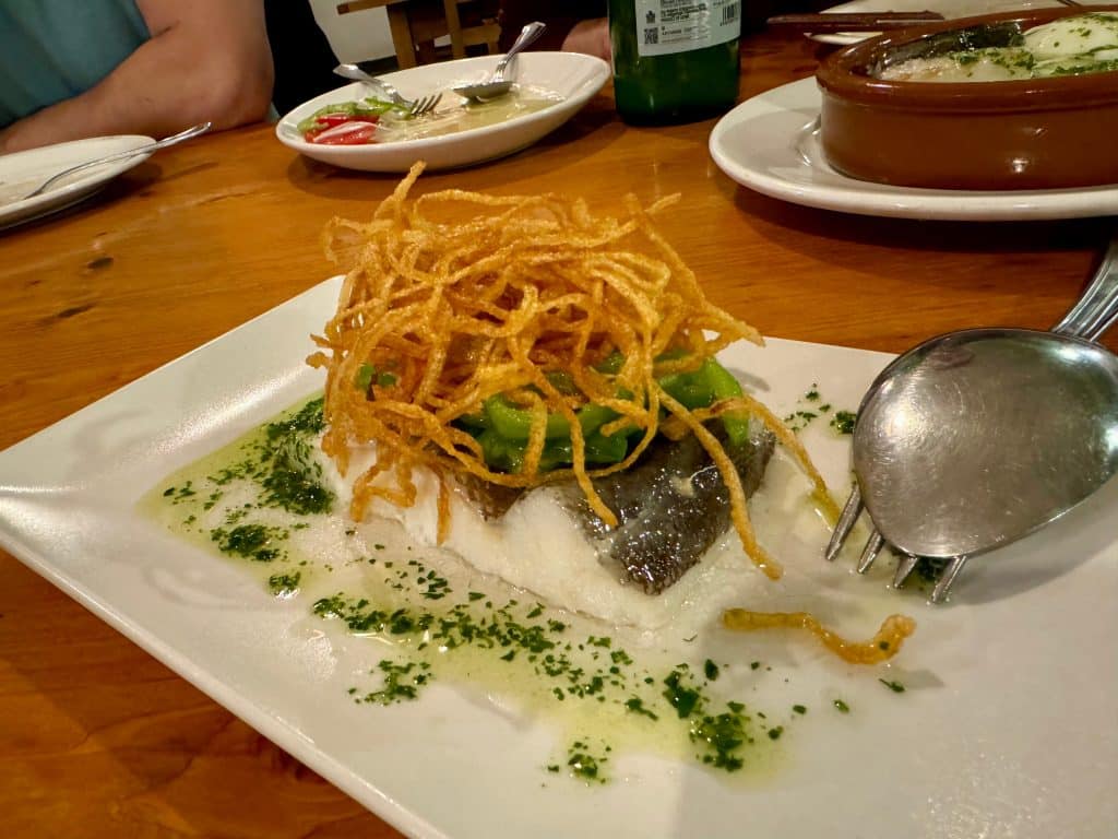 A big slice of cod topped with fried onions and a green sauce.