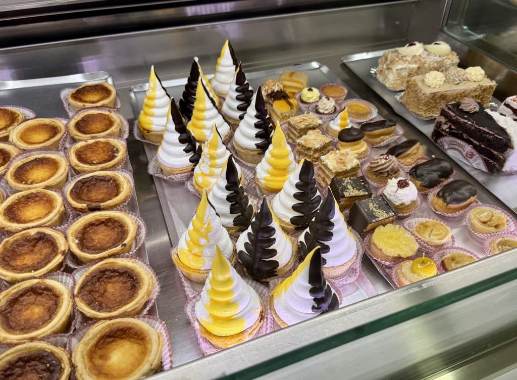 A shelf filled with pastries, including cone-shaped meringues toped with yellow and black.