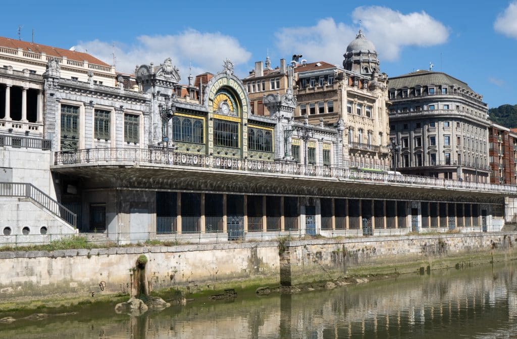 An old-fashioned train station sitting on the edge of the river in Bilbao.