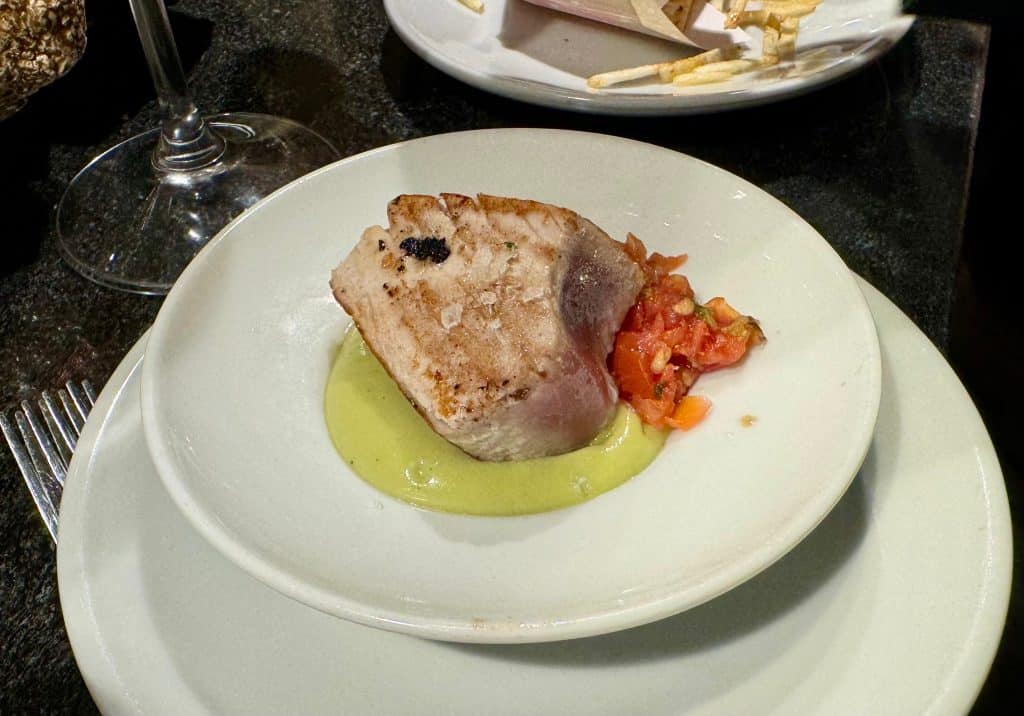 A small plate of fish with some peppers on the side.