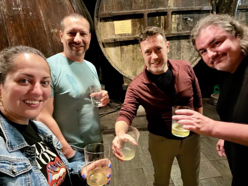 Kate and three friends toasting glasses of cider, a huge cider barrel behind them.