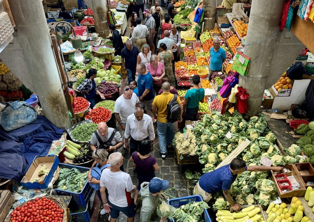An overhead view of a bustling produce market in Mauritius with people selling lots of fruits and vegetables.