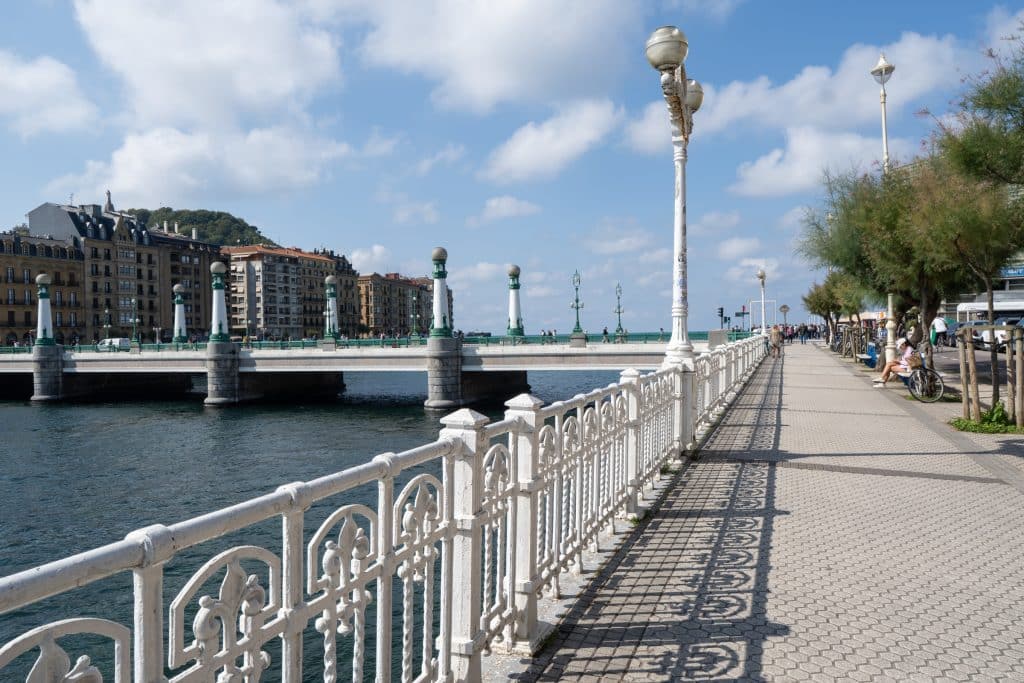 A white fence along a bridge crossing a river in San Sebastián.