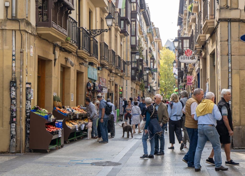 A group of men walking together down a street in the old town, lots of wrought iron balconies on the windows.