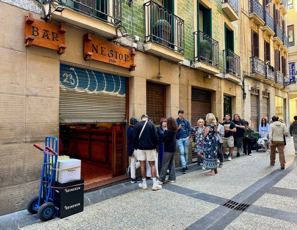 A long line of people waiting at Bar Nestor, as the main door is half open.