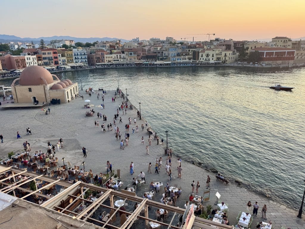 Chania's waterfront bathed in sunset colors, lots of people walking along the water