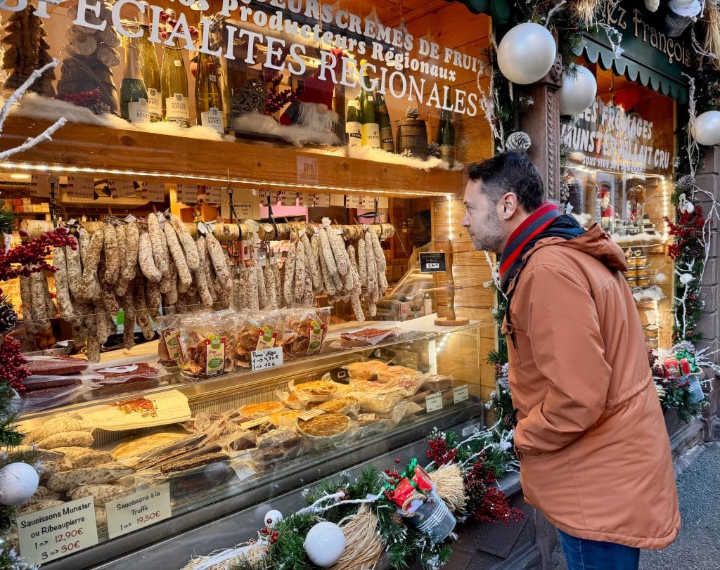 Charlie standing in front of a booth, looking at sausages.