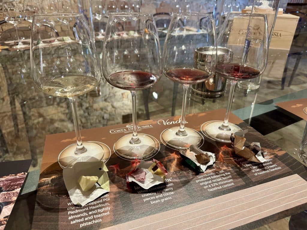 Four tasting glasses of wine with four half-eaten pieces of chocolate in front of them.