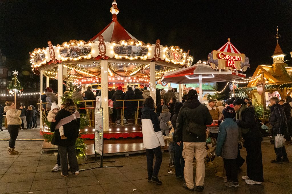 People gathered around a brightly lit carousel bar at night.