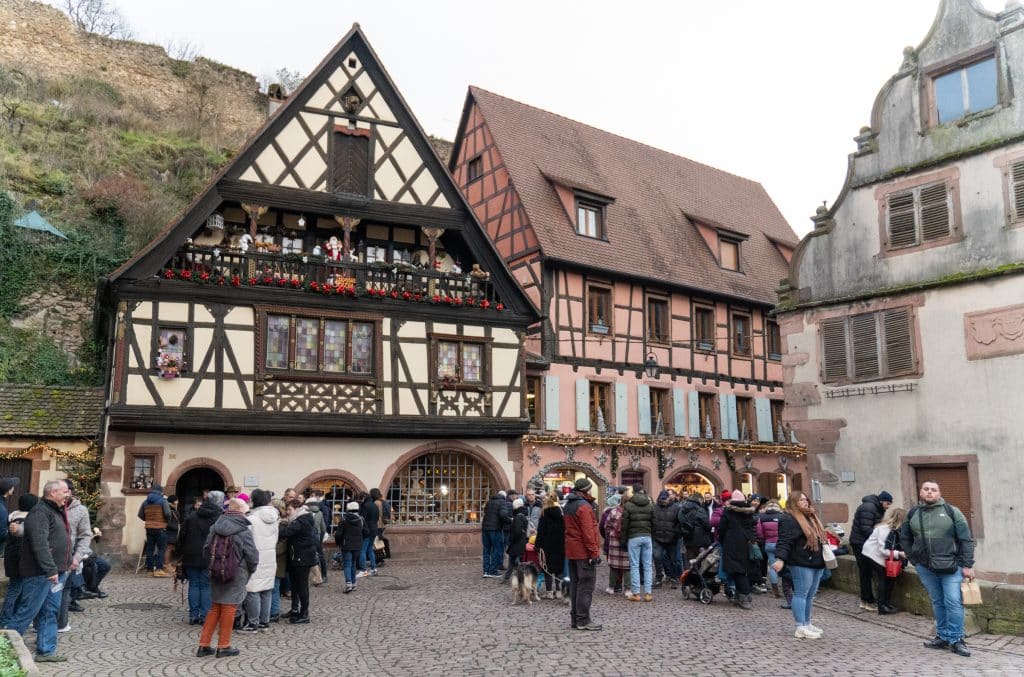 Picture-perfect cream and brown half-timbered buildings covered with Christmas garlands, and lots of people below.