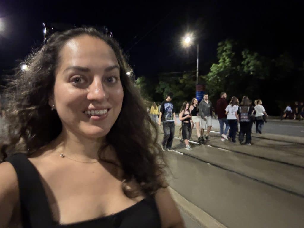 Kate taking a selfie while walking down an empty street with dozens of other people.