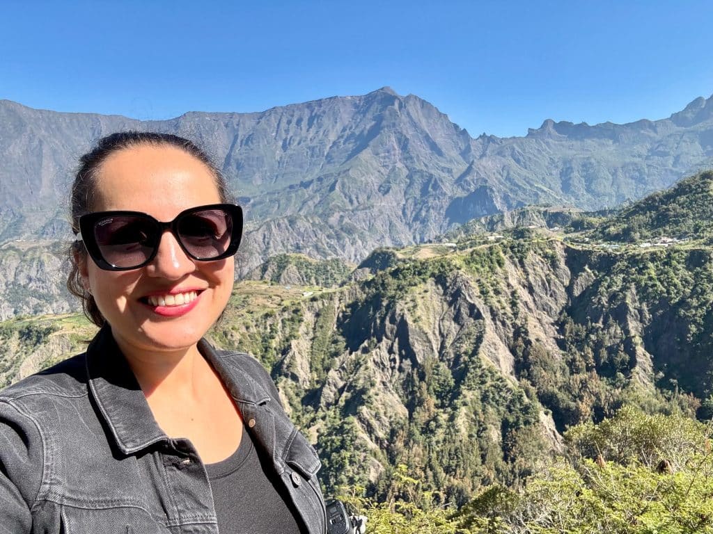 Kate taking a selfie in front of craggy green mountains on Reunion Island.