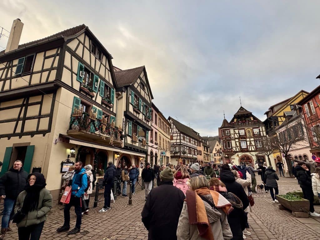 Another small town with half-timbered beige and brown buildings, covered with Christmas decorations and surrounded by crowds.