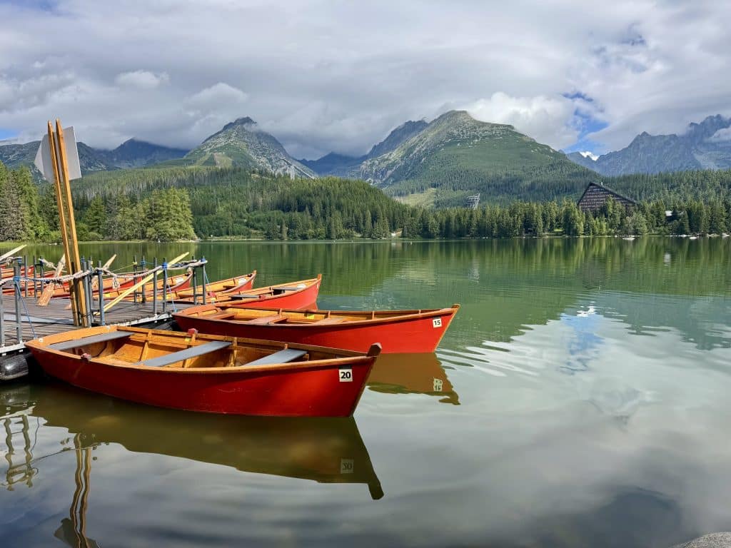 Several bright red canoes perched on a glassy lake surrounded by mountains.