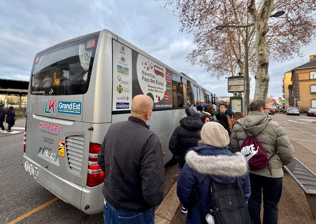 A group of people standing in line for a shuttle bus.