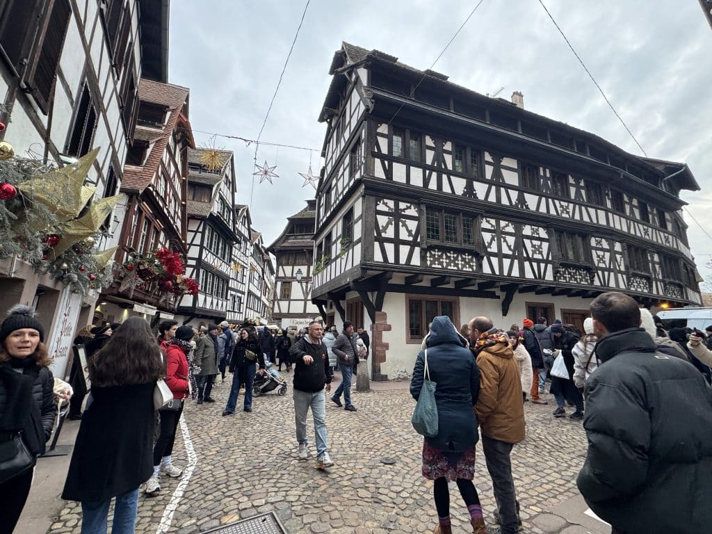 People walking toward a large half-timbered house in the old town of Strasbourg.