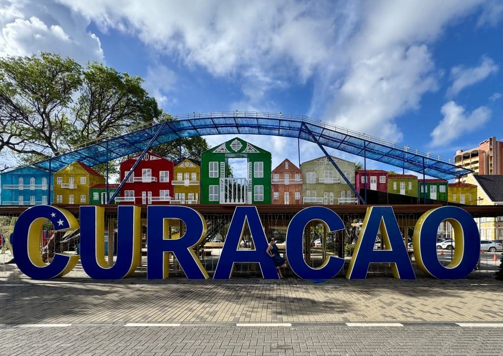 A giant sign reading "Curacao" with Kate posing between the A and C.
