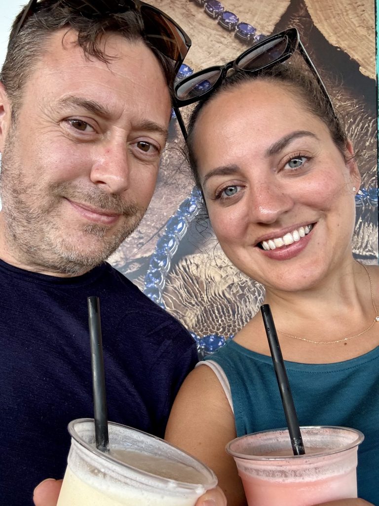 Charlie and Kate taking a smiling selfie together, each drinking a frozen drink.