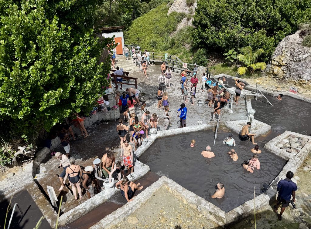 Groups of people lounging in the dark gray geothermal mud baths.