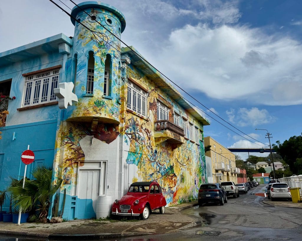 A brightly painted yellow and blue building with a turret, and a little red mini Cooper parked out front.