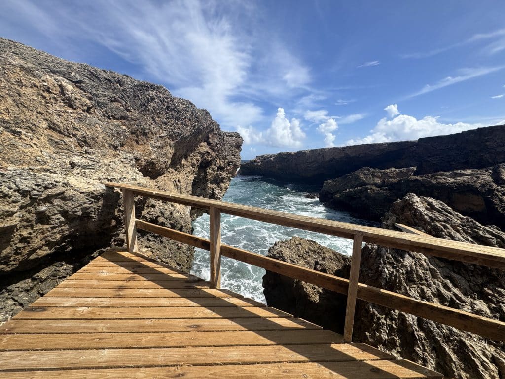 A wooden platform on the edge of the crashing sea, cliffs on each side.