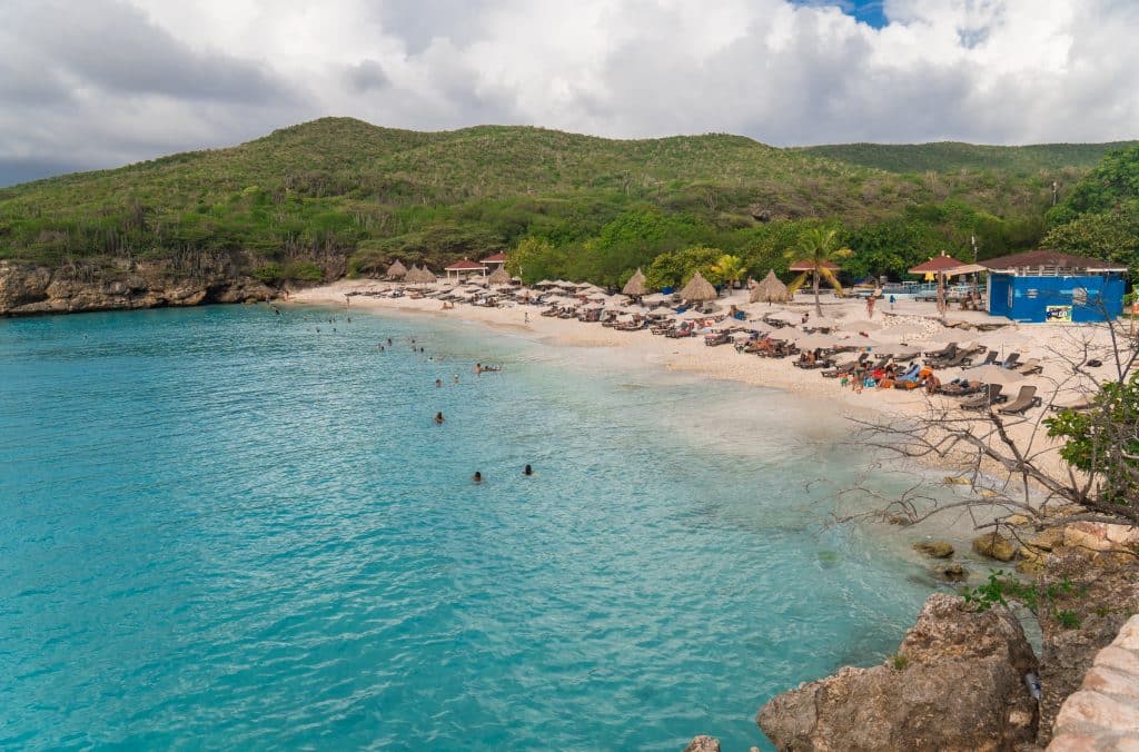 A large bay with bright turquoise water next to a crescent-shaped beach.