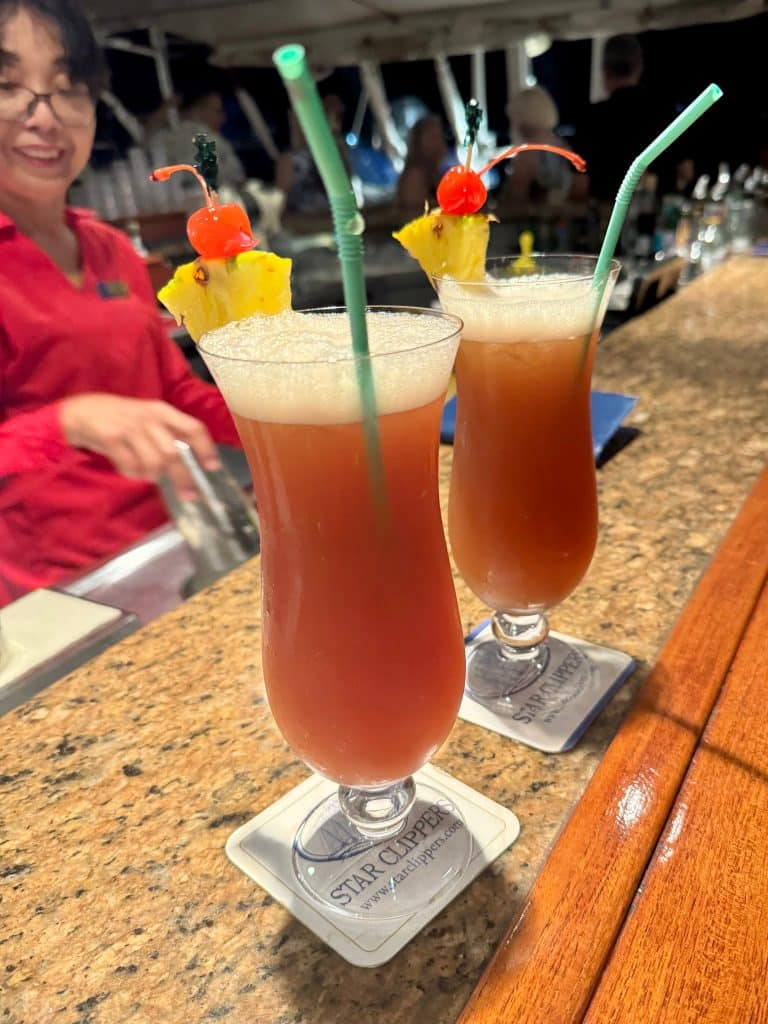 Two tropical cocktails topped with pineapple and cherries.