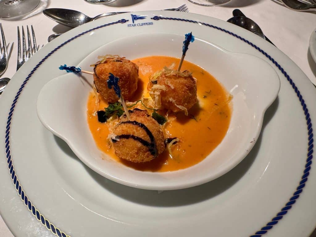 Three small fried balls in a bowl of orange sauce.