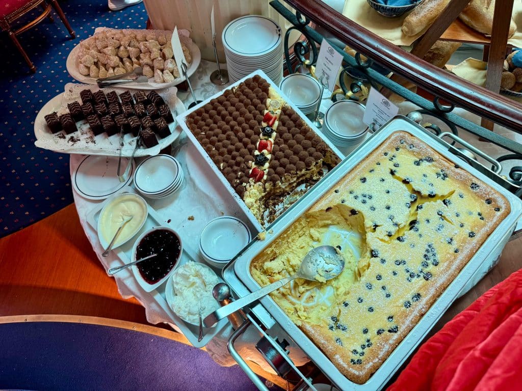 A dessert buffet with several cakes and a tiramisu.