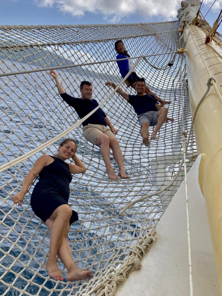 Kate, Charlie and two friends lying on rope netting over the sea.