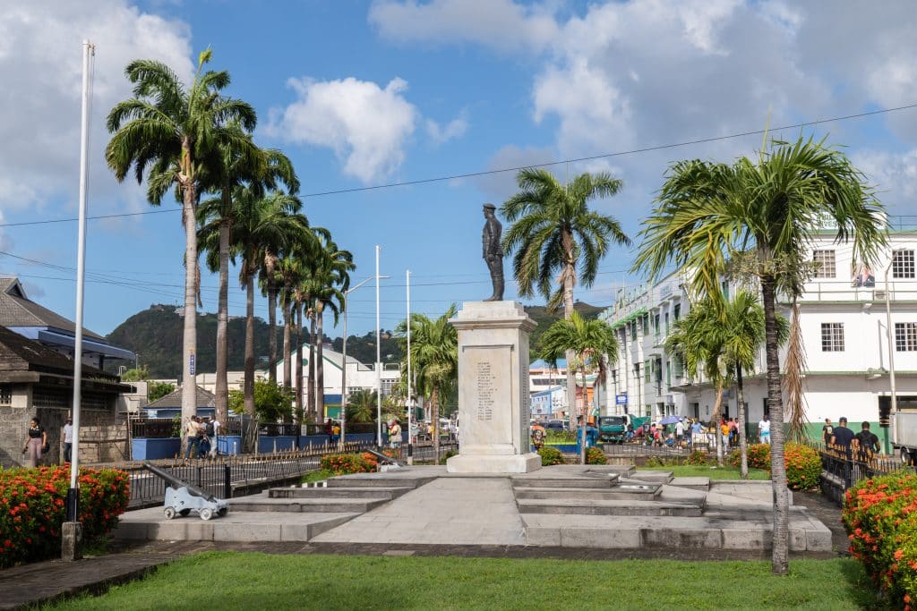 A main square in Kingstown with a statue of a man surrounded by palm trees.