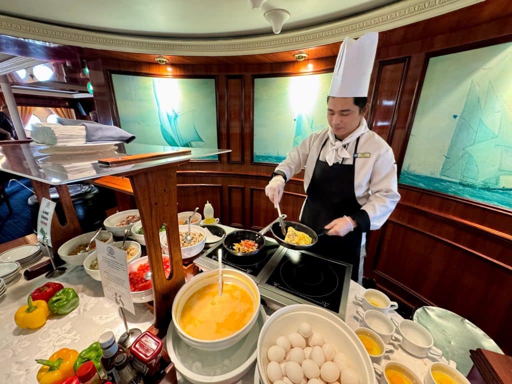 A chef in a tall hat making an omelet at a station.